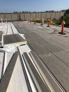Rigid polyiso continuous insulation boards stacked on a low-slope roof ready for membrane installation